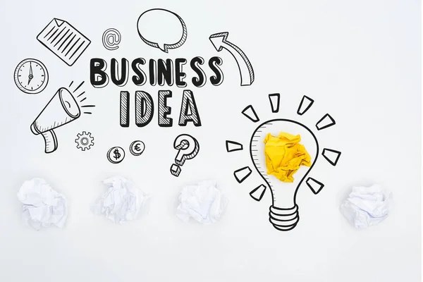 Вид надписи бизнес-идеи рядом с иллюстрацией и мятые бумажные шарики на белом фоне, бизнес-концепция — стоковое фото