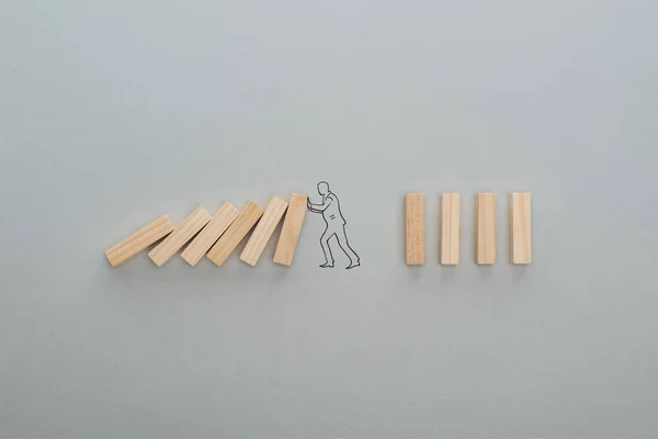 Vue du dessus de l'homme dessiné poussant des blocs de bois sur fond gris, concept d'entreprise — Photo de stock