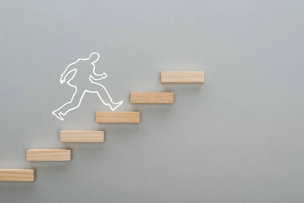 Vista superior del hombre dibujado corriendo sobre bloques de madera que simbolizan la escalera de carrera sobre fondo gris, concepto de negocio - foto de stock