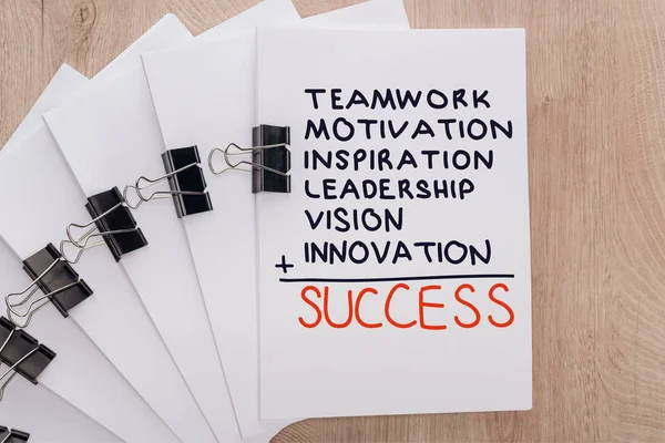 Vista dall'alto di fogli di carta bianca organizza con clip legante e lavoro di squadra, motivazione, ispirazione, leadership, visione, innovazione, parole di successo sul tavolo di legno, concetto di business — Foto stock