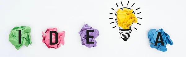 Tiro panorâmico de bolas de papel amassadas multicoloridas, palavra ideia e ilustração lâmpada no fundo branco, conceito de negócio — Fotografia de Stock