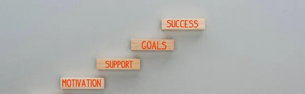Panoramica di blocchi di legno con motivazione, supporto, obiettivi, parole di successo su sfondo grigio, concetto di business — Foto stock
