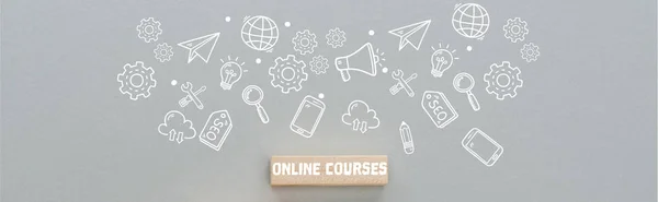 Panoramic shot of wooden block with online courses inscription and multimedia icons illustration on grey background, business concept — Stock Photo