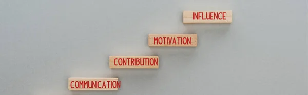 Tiro panorâmico de blocos de madeira com comunicação, contribuição, motivação, palavras de influência em fundo cinza, conceito de negócio — Fotografia de Stock