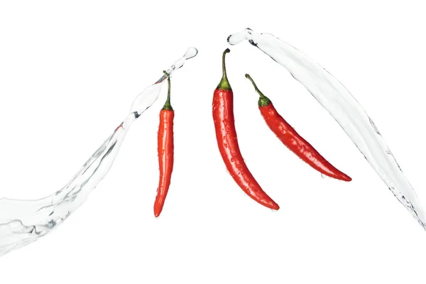 Chiles rojos picantes brillantes con salpicaduras de agua clara aisladas en blanco - foto de stock