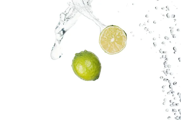Limes fraîches vertes avec éclaboussure d'eau claire isolées sur blanc — Photo de stock