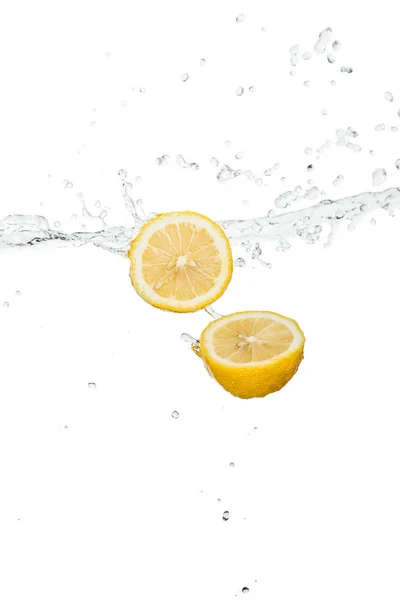 Mitades de limón amarillo con salpicaduras de agua clara y gotas aisladas en blanco - foto de stock