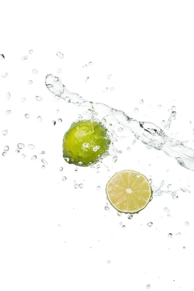 Limão inteiro fresco verde e metade com respingo de água clara e gotas isoladas em branco — Fotografia de Stock