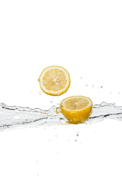 Limoni tagliati gialli con spruzzi d'acqua e gocce isolate sul bianco — Foto stock