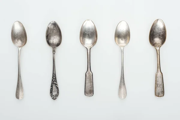 Top view of shiny aged silver empty spoons in row on white background — Stock Photo