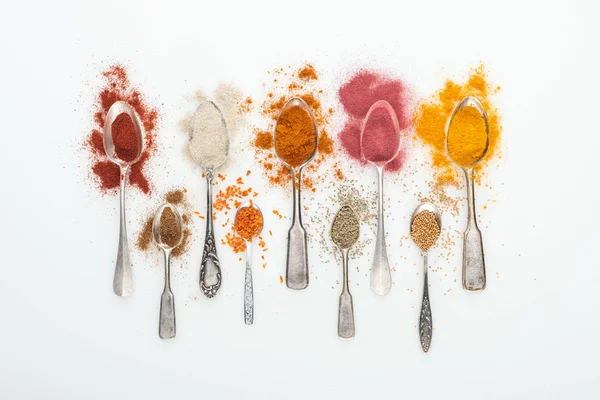 Top view of colorful spices in silver spoons on white background — Stock Photo