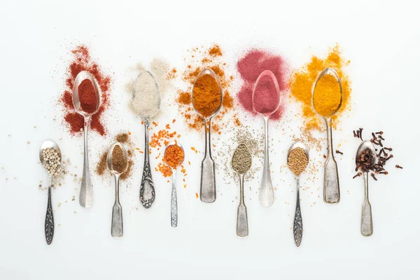 Top view of various bright spices in silver spoons on white background — Stock Photo