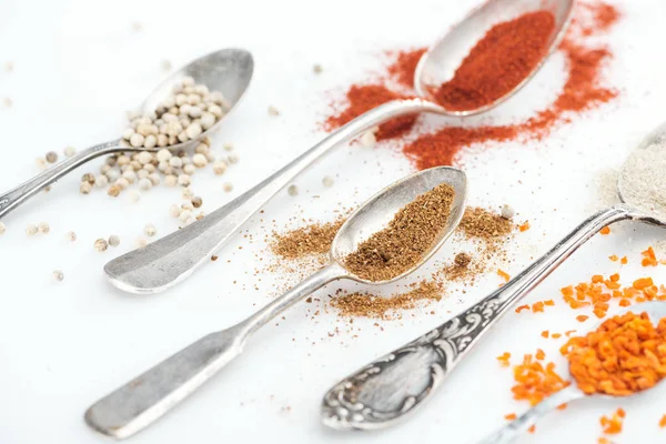 Close up view of colorful spices in silver spoons on white background — Stock Photo