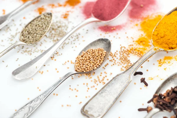 Close up view of various bright spices in silver vintage spoons on white background — Stock Photo