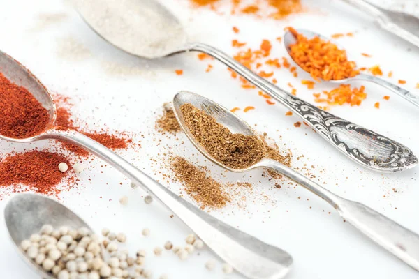 Close up view of various colorful spices in silver retro spoons on white background — Stock Photo