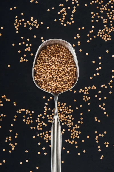Top view of mustard in silver spoon on black background — Stock Photo