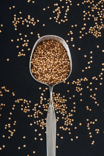 Vue de dessus de moutarde en cuillère argentée sur fond noir — Photo de stock