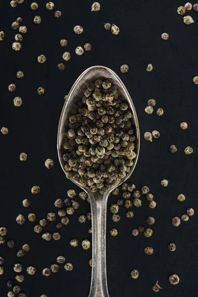 Top view of pepper in silver spoon on black background — Stock Photo