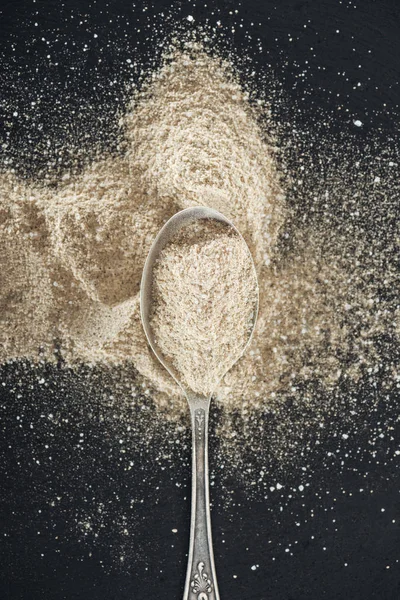 Vista dall'alto di aglio in polvere in cucchiaio d'argento su sfondo nero — Foto stock