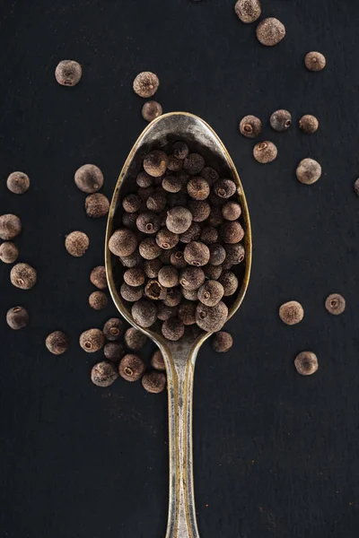 Top view of black pepper in silver spoon on black background — Stock Photo