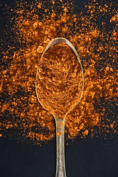 Top view of turmeric in silver spoon on black background — Stock Photo