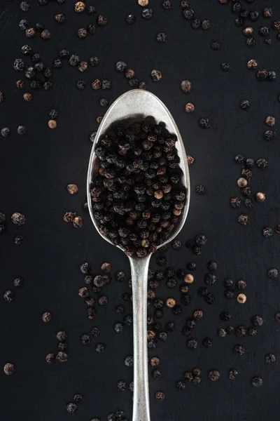 Top view of black pepper in silver spoon on black background — Stock Photo