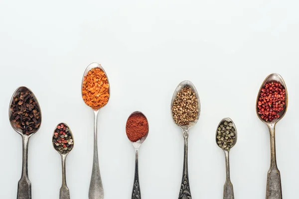 Top view of colorful spices in silver spoons on white background with copy space — Stock Photo