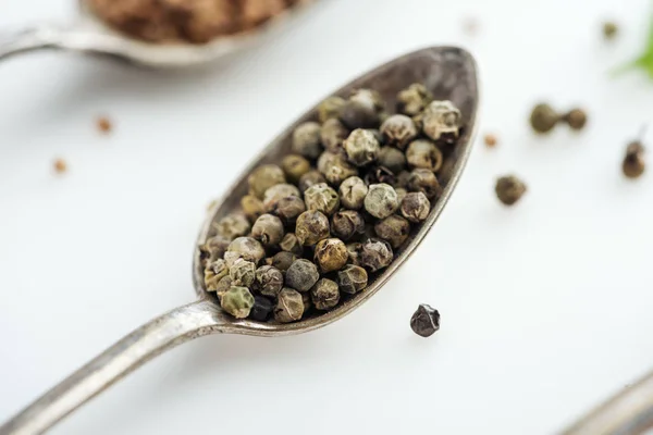 Close up view of pepper in silver spoon on white background — Stock Photo