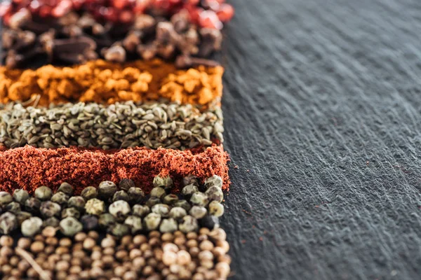 Close up view of traditional bright indian spices on textured black background — Stock Photo