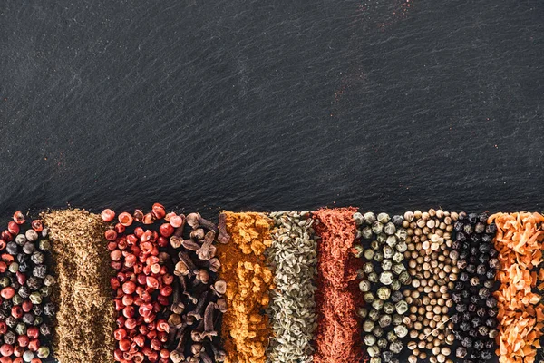 Vue de dessus des épices indiennes lumineuses traditionnelles sur fond noir texturé avec espace de copie — Photo de stock