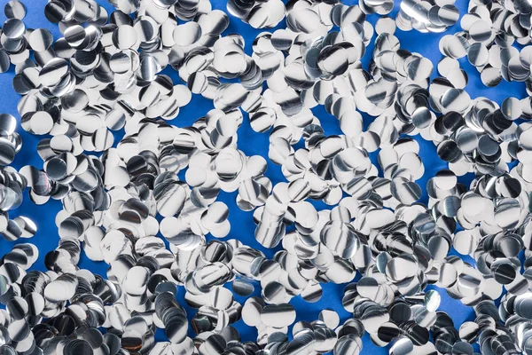 Vista superior de peças de prata de confete no fundo azul — Fotografia de Stock