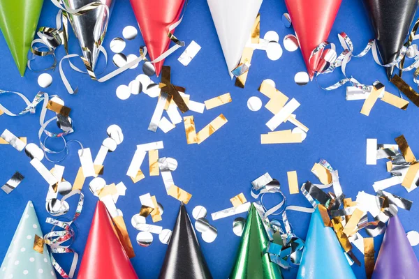 Bunte Party-Hüte und silbernes Konfetti auf blauem Hintergrund — Stockfoto