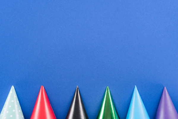 Vista dall'alto di cappelli da festa multicolore su sfondo blu — Foto stock