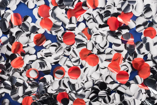 Vue du dessus des confettis abstraits en argent et rouge sur fond bleu — Photo de stock
