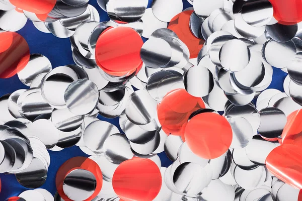 Close up view of silver and red confetti on blue background — Stock Photo