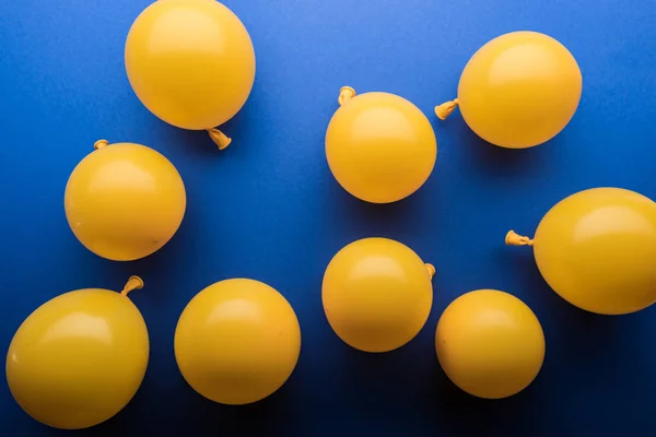 Ballons jaunes décoratifs sur fond bleu vif — Photo de stock