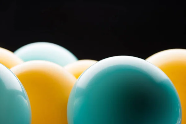 Vue rapprochée de ballons lumineux jaunes et bleus isolés sur noir — Photo de stock