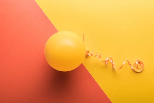 Top view of yellow balloon on coral and yellow background — Stock Photo