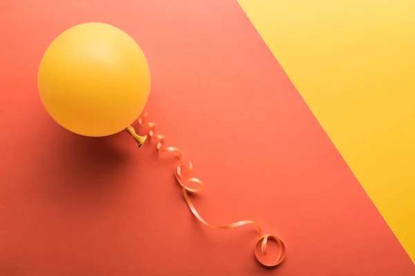 Top view of yellow balloon on coral background — Stock Photo