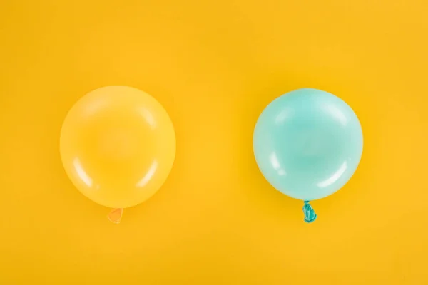 Vista superior de globos azules y amarillos sobre fondo amarillo - foto de stock