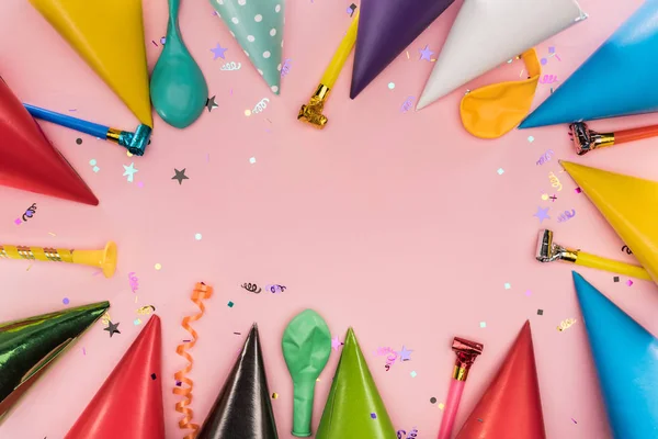 Top view of party horns, caps and confetti on pink background — Stock Photo