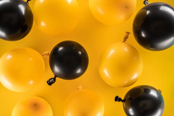 Top view of yellow and black balloons on bright background — Stock Photo