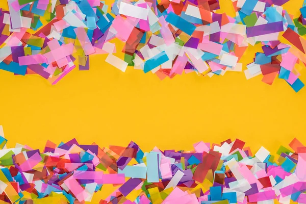 Vue du dessus du cadre confetti multicolore sur fond jaune — Photo de stock