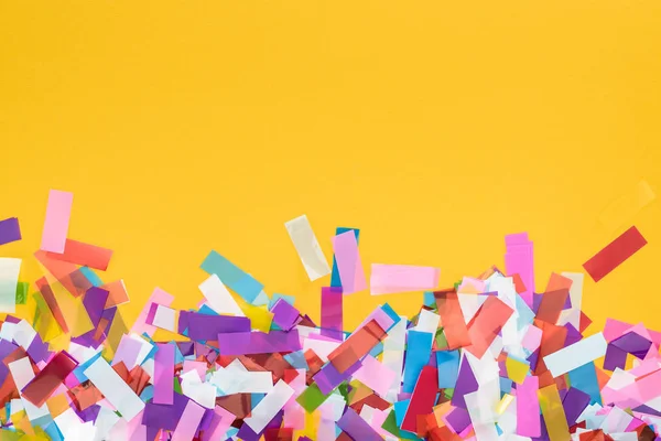 Вид сверху на многоцветные конфетти на желтом праздничном фоне — стоковое фото