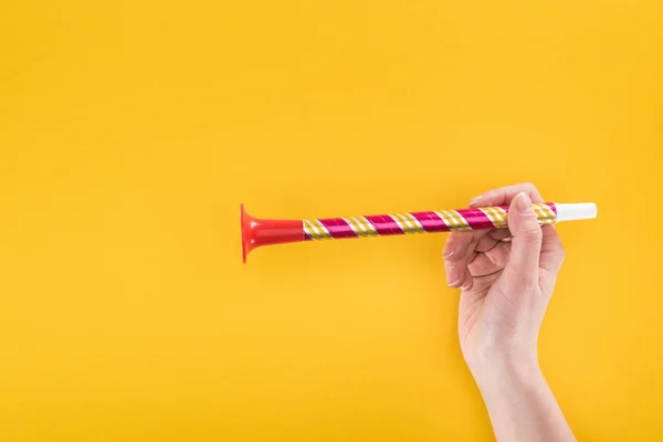 Partial view of woman holding red party horn on yellow background — Stock Photo