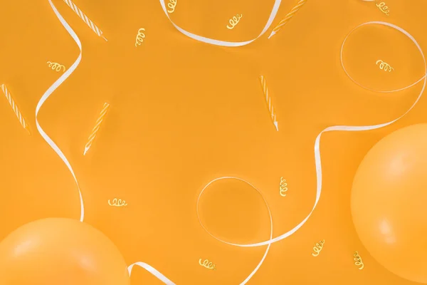 Fita branca e ouro confete e velas no fundo laranja — Fotografia de Stock