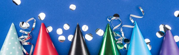 Panoramic shot of party hats and confetti on blue background — Stock Photo