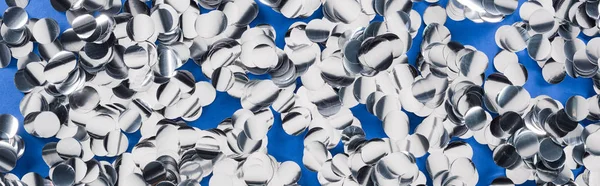 Panoramic shot of silver confetti on blue festive background — Stock Photo