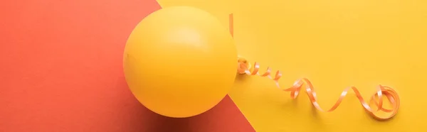 Panoramic shot of yellow balloon on coral and yellow background — Stock Photo