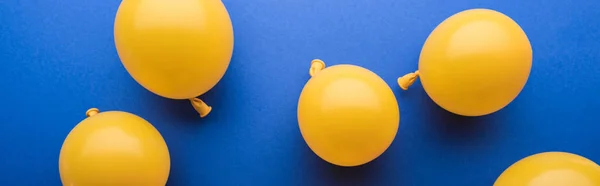 Foto panorámica de globos amarillos festivos sobre fondo azul - foto de stock